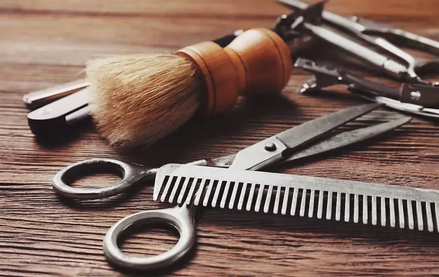 Barber's brush, comb and scissors on a wooden table